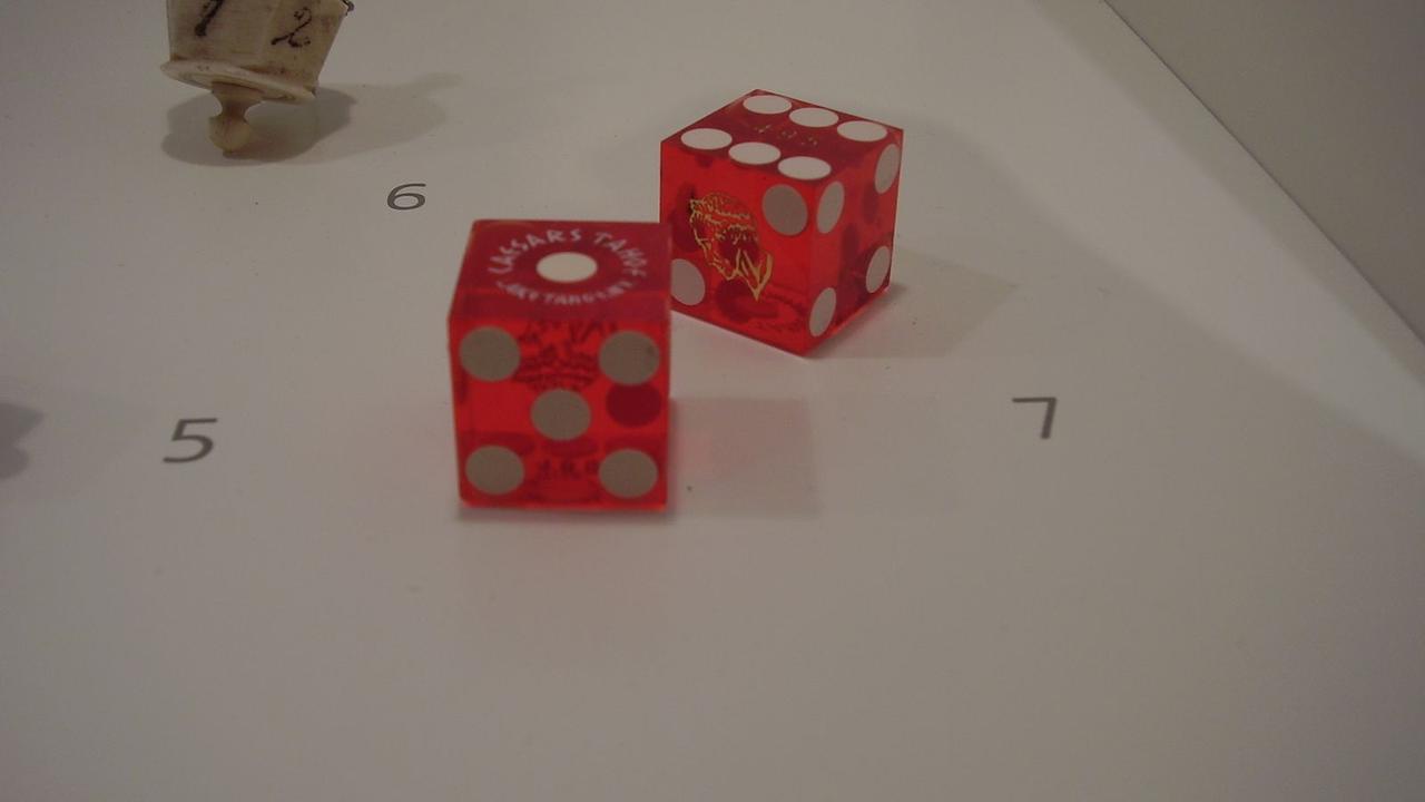 Two red casino dice on a white surface