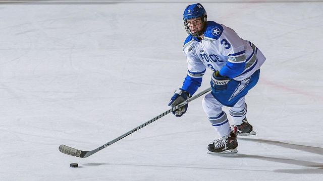 An ice hockey player carrying the puck up the ice