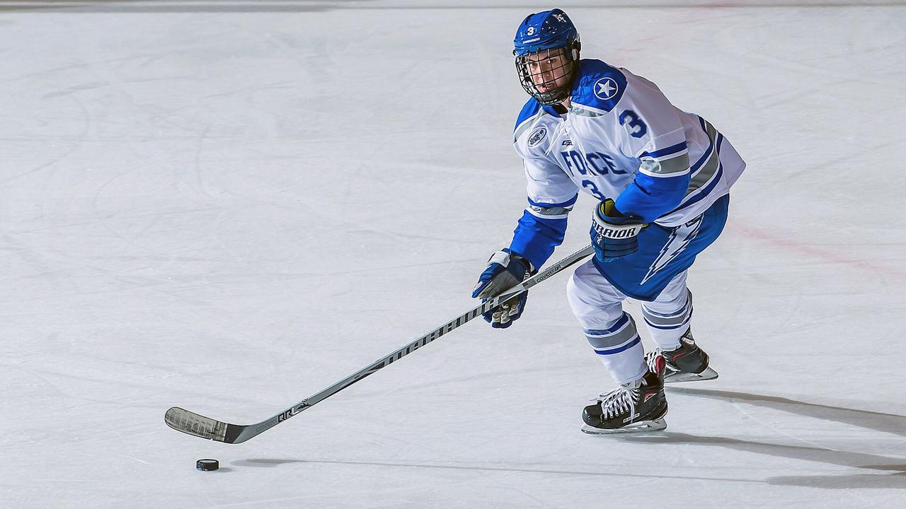 An ice hockey player carrying the puck up the ice
