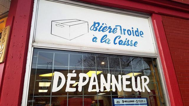 Hand-painted dépanneur sign in a red shop window in Quebec