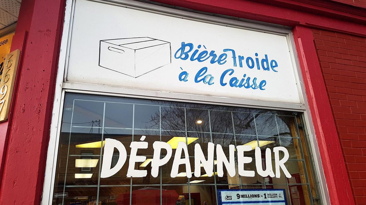 Hand-painted dépanneur sign in a red shop window in Quebec