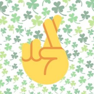 Fingers Crossed Against Four Leafed Clover Background